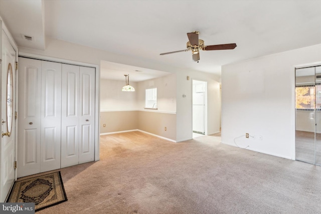 carpeted empty room with a wealth of natural light and ceiling fan