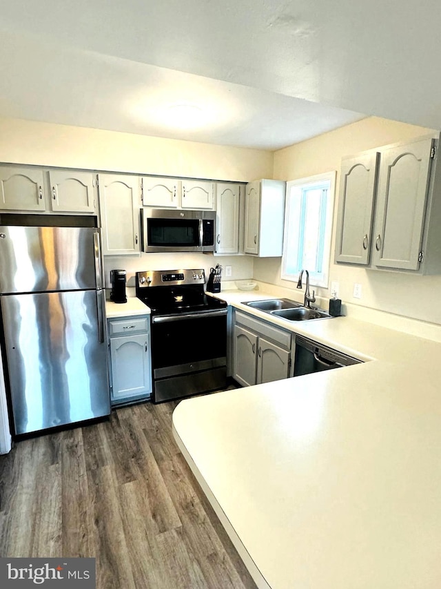 kitchen featuring a sink, dark wood finished floors, appliances with stainless steel finishes, and light countertops