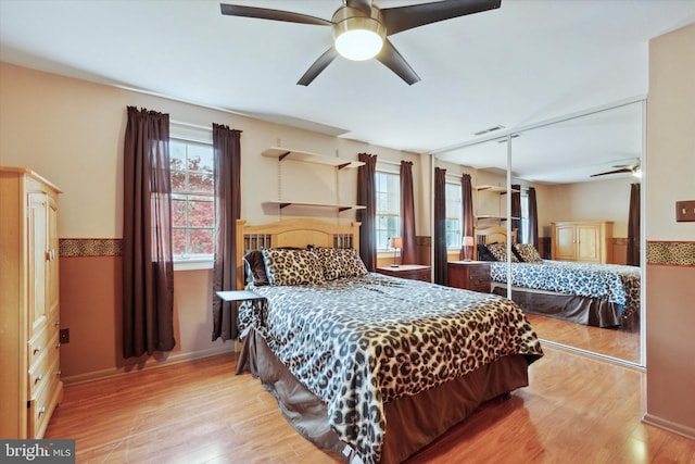 bedroom with light wood-type flooring, ceiling fan, and a closet