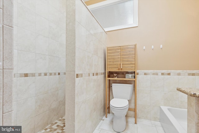 bathroom with a bath, tile patterned flooring, toilet, and tile walls