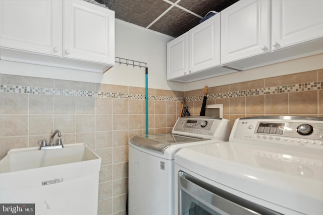 laundry area with tile walls, cabinets, and washer and dryer