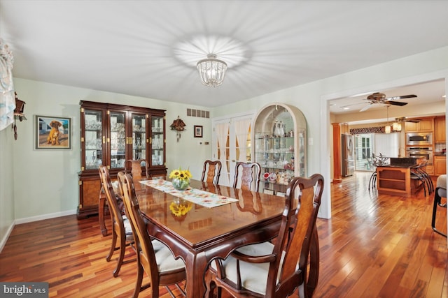 dining room featuring hardwood / wood-style floors, a healthy amount of sunlight, and ceiling fan with notable chandelier