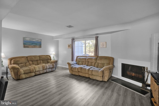 living area featuring visible vents, baseboards, wood finished floors, and a fireplace