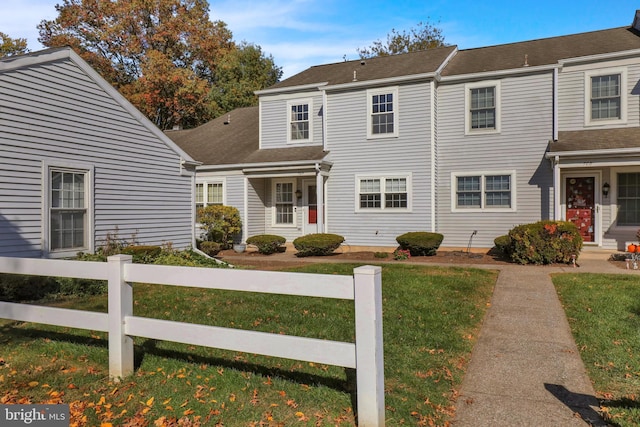 view of property featuring a shingled roof, a front yard, and fence