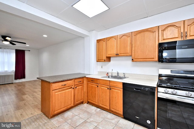 kitchen with sink, radiator, kitchen peninsula, ceiling fan, and black appliances