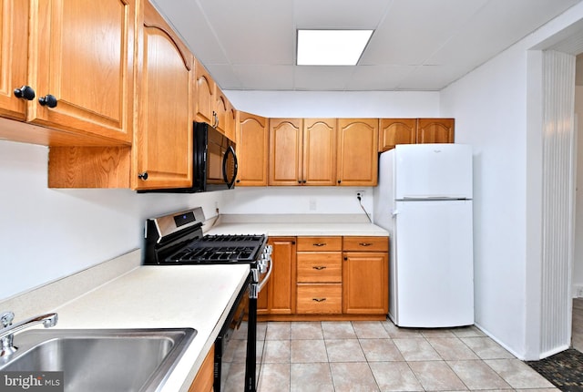 kitchen with sink, light tile patterned floors, white refrigerator, stainless steel range with gas cooktop, and a drop ceiling