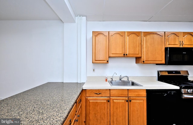 kitchen featuring sink, a drop ceiling, and black appliances