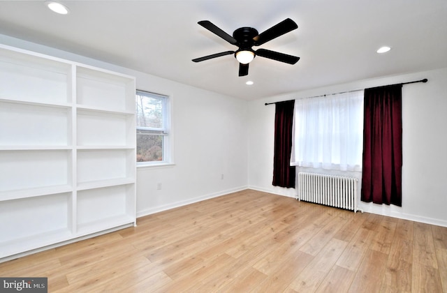 empty room featuring radiator, light hardwood / wood-style flooring, and ceiling fan