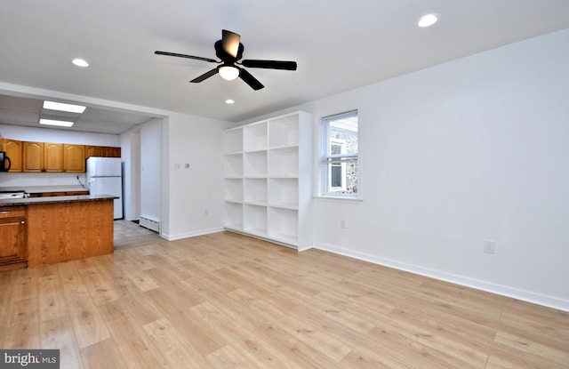 unfurnished living room with ceiling fan, light hardwood / wood-style floors, and a baseboard heating unit