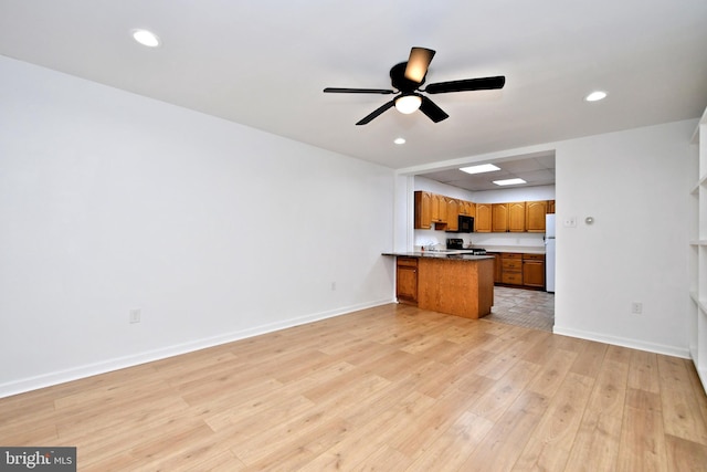 kitchen featuring ceiling fan, white fridge, light hardwood / wood-style floors, and kitchen peninsula