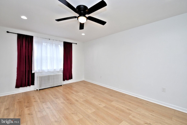 empty room with radiator heating unit, light hardwood / wood-style floors, and ceiling fan