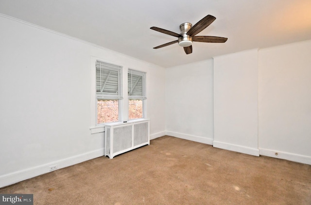 empty room featuring radiator, crown molding, light colored carpet, and ceiling fan