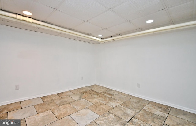 basement with a drop ceiling and light tile patterned floors