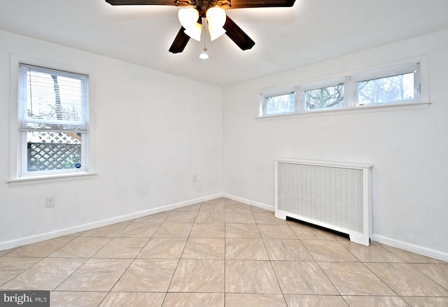 unfurnished room featuring ceiling fan, radiator, and light tile patterned floors