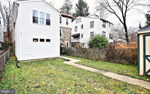 rear view of property with a lawn and a shed