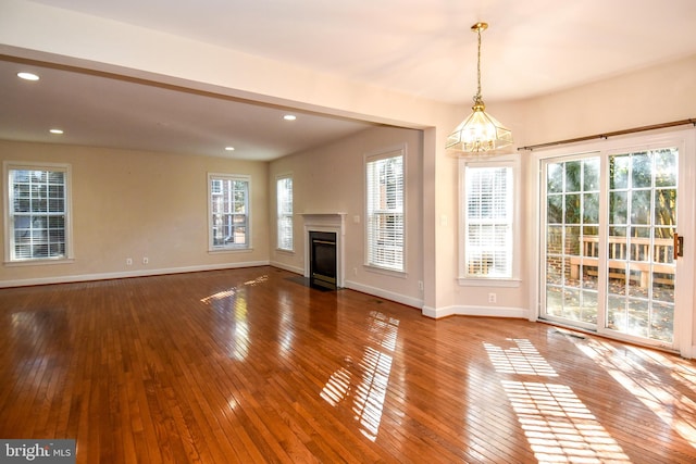 unfurnished living room with a chandelier and hardwood / wood-style flooring