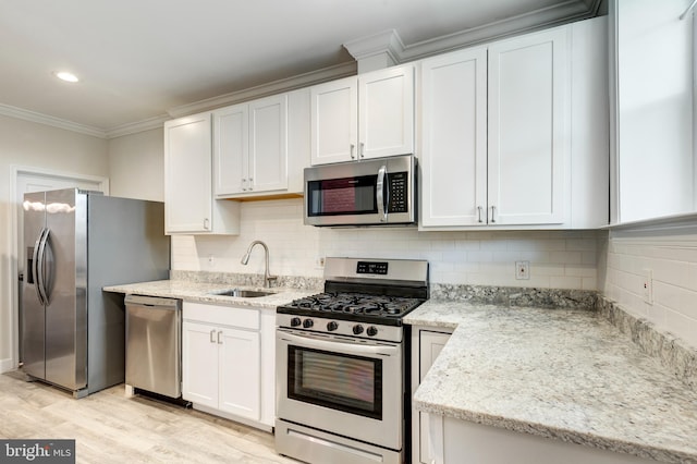 kitchen featuring stainless steel appliances, sink, white cabinets, light stone counters, and light hardwood / wood-style floors