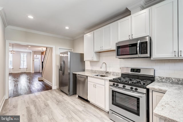 kitchen featuring stainless steel appliances, backsplash, sink, white cabinets, and light hardwood / wood-style floors