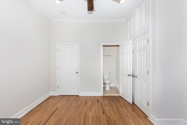 unfurnished bedroom with crown molding, connected bathroom, light wood-type flooring, and ceiling fan