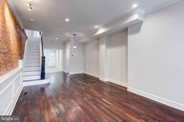 unfurnished living room with crown molding, brick wall, and dark wood-type flooring