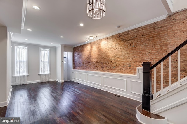 interior space with crown molding, brick wall, and dark hardwood / wood-style flooring