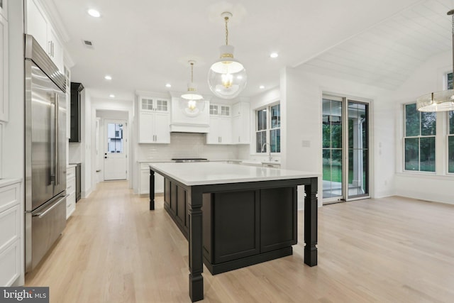 kitchen featuring a center island, pendant lighting, light wood-type flooring, white cabinetry, and stainless steel built in refrigerator