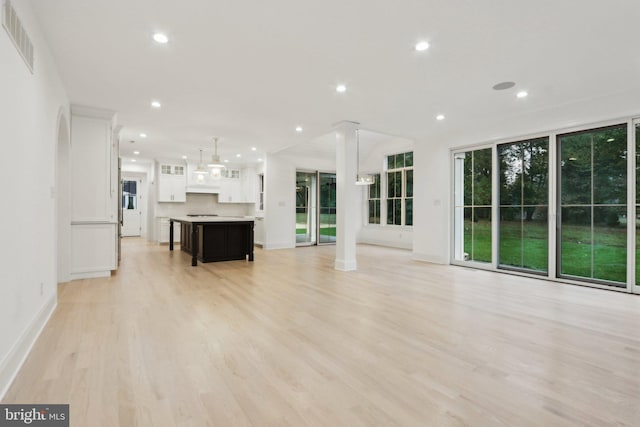 unfurnished living room featuring light hardwood / wood-style flooring and decorative columns