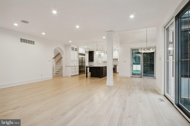 unfurnished living room featuring an inviting chandelier and light hardwood / wood-style floors