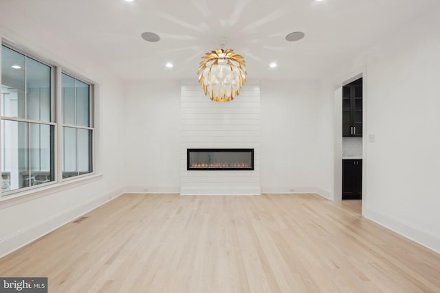 unfurnished living room featuring a large fireplace and light hardwood / wood-style floors