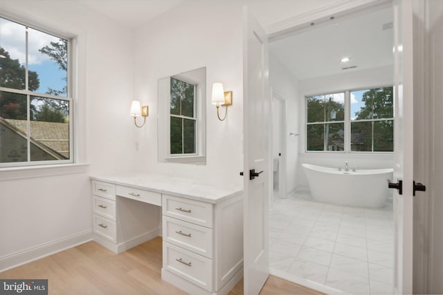 bathroom with vanity, a tub to relax in, wood-type flooring, and plenty of natural light