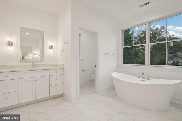 bathroom featuring toilet, vanity, and a bath