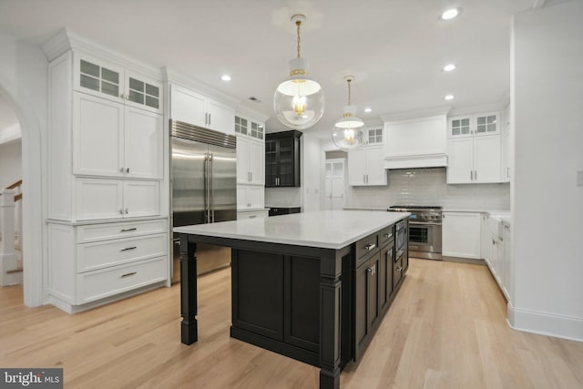 kitchen with white cabinets, a center island, premium appliances, and pendant lighting