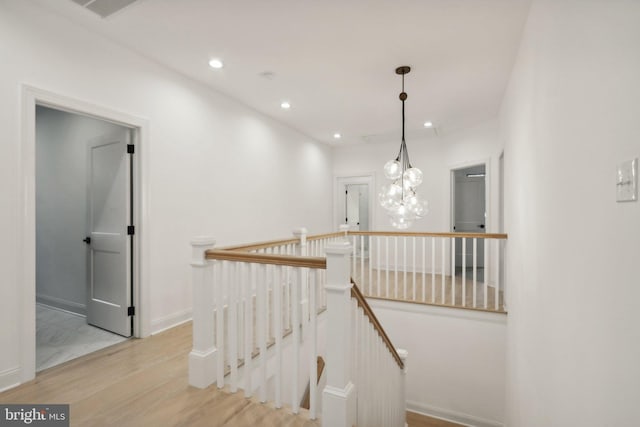 hall featuring an inviting chandelier and light wood-type flooring