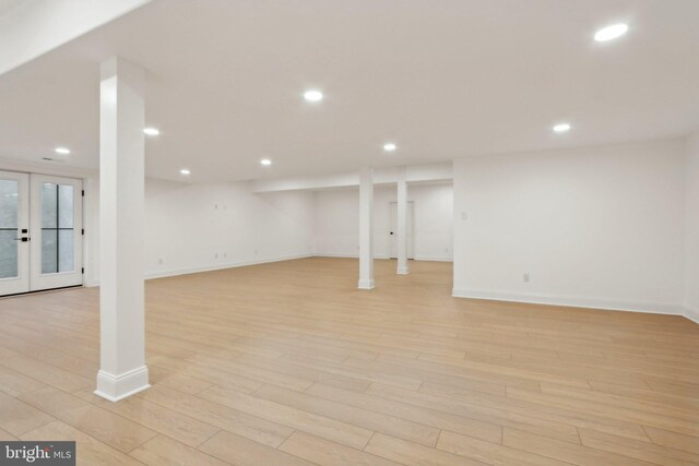 basement with french doors and light hardwood / wood-style floors