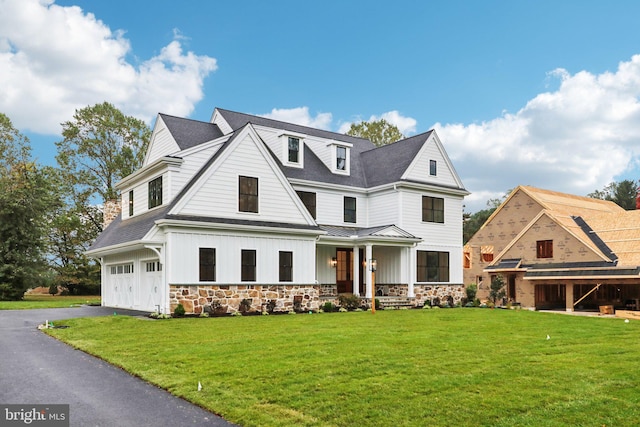 view of front facade featuring a front yard, a garage, and a porch