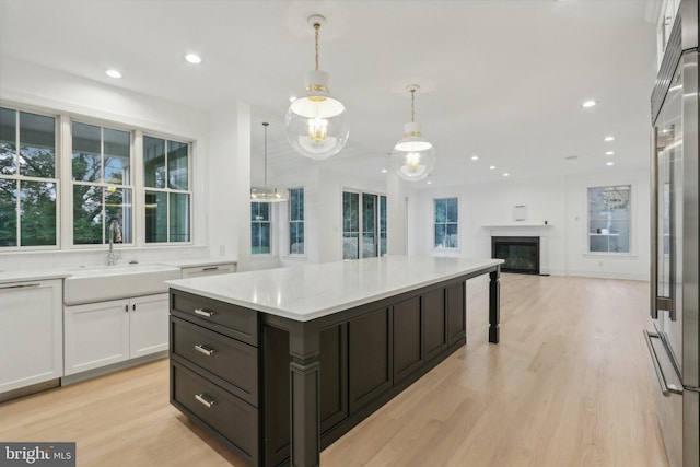 kitchen with sink, light hardwood / wood-style flooring, decorative light fixtures, and a healthy amount of sunlight