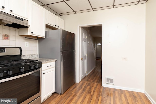 kitchen featuring decorative backsplash, a drop ceiling, white cabinets, appliances with stainless steel finishes, and dark hardwood / wood-style flooring