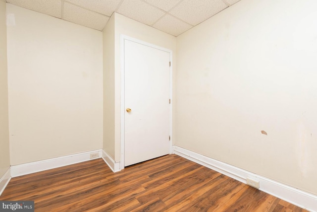 empty room featuring dark wood-type flooring and a drop ceiling