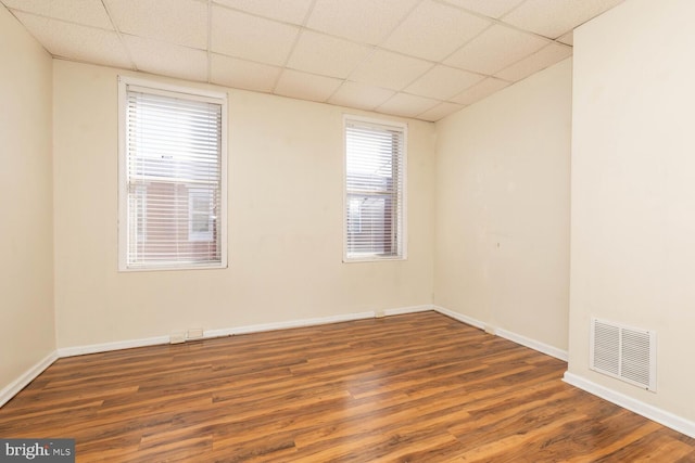 unfurnished room with a drop ceiling, dark hardwood / wood-style floors, and a healthy amount of sunlight