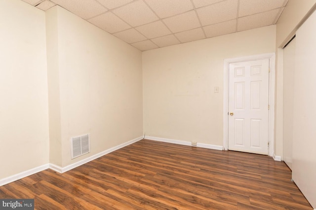 spare room with dark wood-type flooring and a paneled ceiling