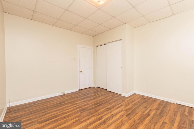 spare room with a paneled ceiling and dark wood-type flooring