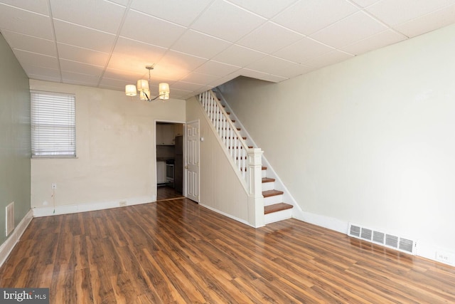 interior space with dark wood-type flooring, a drop ceiling, and an inviting chandelier