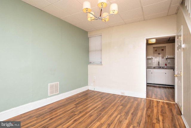 empty room featuring dark wood-type flooring, a paneled ceiling, and sink