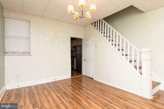 interior space featuring a drop ceiling, a chandelier, and dark hardwood / wood-style flooring