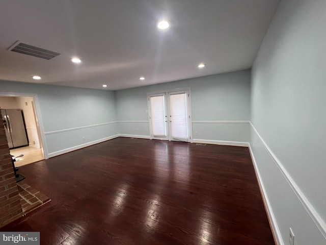 empty room featuring french doors, a fireplace, and dark hardwood / wood-style floors