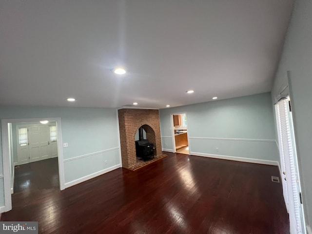 unfurnished living room with a wood stove and dark hardwood / wood-style flooring