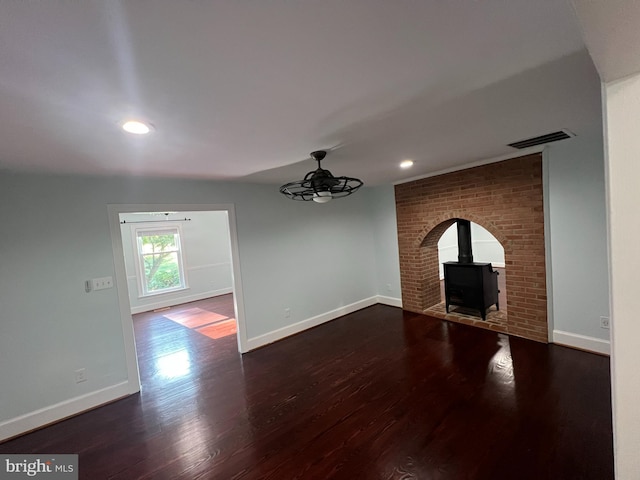 unfurnished living room with dark wood-type flooring and a wood stove