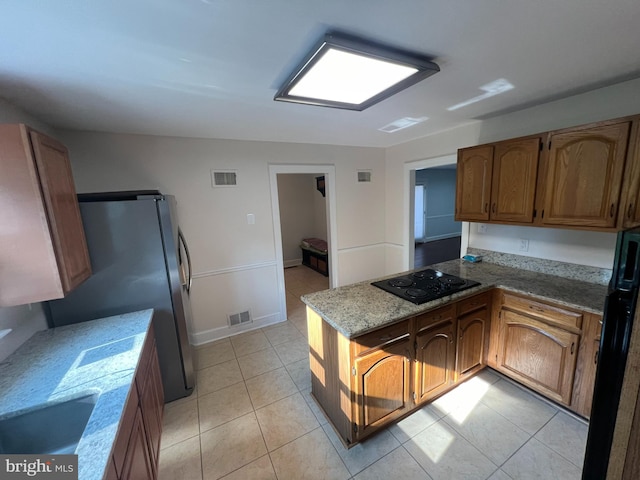 kitchen with black electric cooktop, stainless steel fridge, kitchen peninsula, and light tile patterned floors