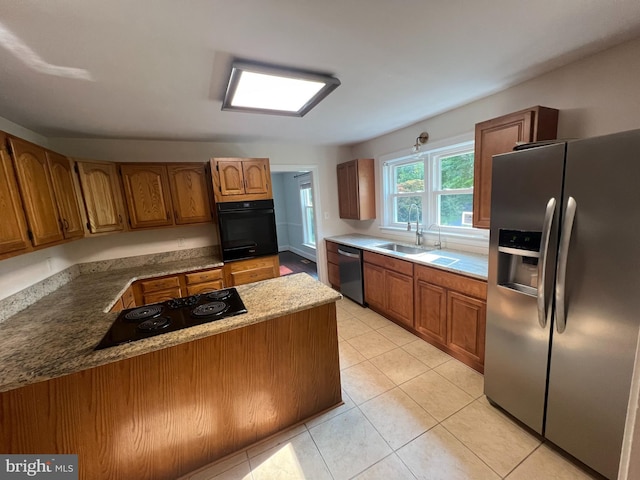 kitchen with stone countertops, kitchen peninsula, sink, black appliances, and light tile patterned flooring