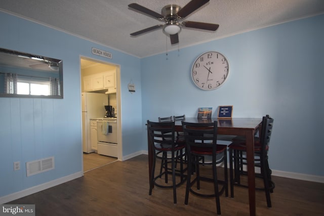 dining room featuring ornamental molding, a textured ceiling, and dark hardwood / wood-style flooring